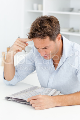 Concentrated man doing a cryptic crossword sitting in his kitche