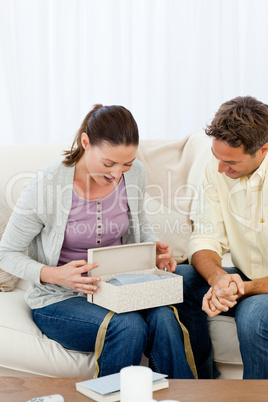 Amazed woman opening a present from his boyfriend on the sofa
