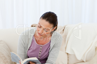 Passionate woman reading a fiction sitting on the sofa