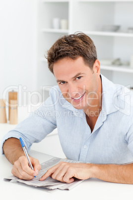 Smart man doing a cryptic crossword sitting in his kitchen