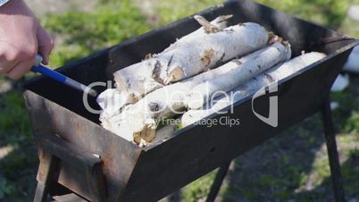 Unidentified man burn a brazier with birch logs