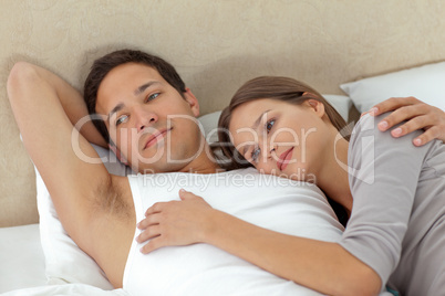 Pensive couple lying in each other's arms