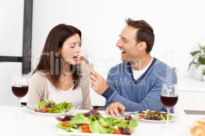 Attentive man giving a tomato to his girlfriend while having lu