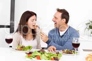 Attentive man giving a tomato to his girlfriend while having lu