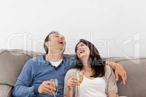 Couple laughing while drinking champagne on the sofa