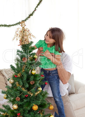 Attentive father holding her daughter to decorate the christmas