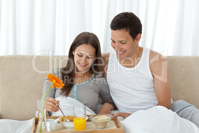 Young woman having breakfast on the bed with her boyfriend