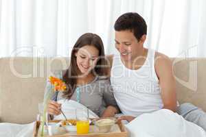 Young woman having breakfast on the bed with her boyfriend