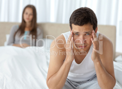 Tired man having a headache sitting on the bed with his girlfrie