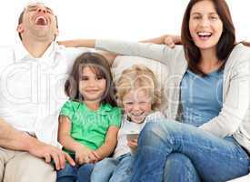 Family laughing while watching television together