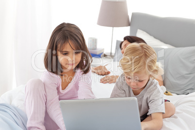 Cute brother and sister on internet while their mother is sleepi