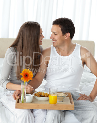 Passionate couple with their breakfast sitting on the bed