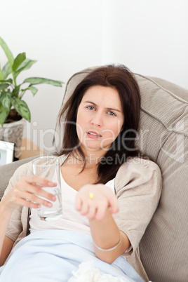 Sick woman showing a pill to the camera