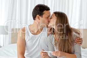 Couple kissing after looking at the result of a pregnancy test