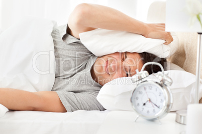 Stressed man looking at his alarm clock ringing