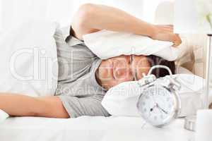 Stressed man looking at his alarm clock ringing