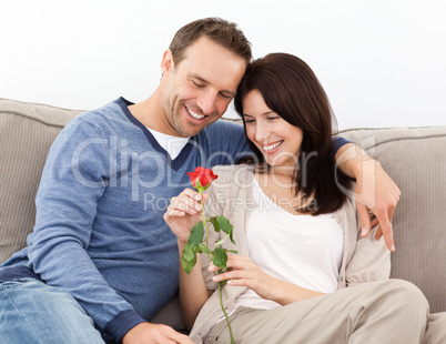 Portrait of a lovely couple looking at a red rose