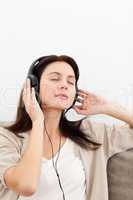 Serene woman listening to the music on the sofa