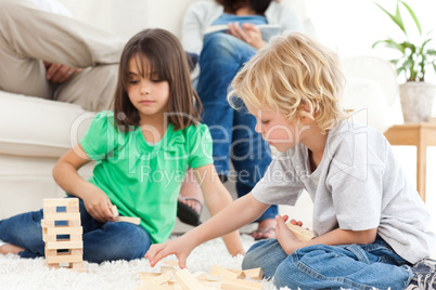 Cute brother and sister playing with dominoes on the floor