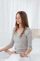 Concentrated woman doing yoga exercises on the bed