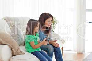 Attentive mother encouraging her daughter playing video games