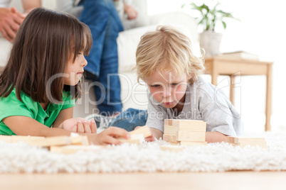 Cute little boy playing dominoes with his sister on the floor