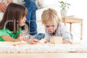 Cute little boy playing dominoes with his sister on the floor