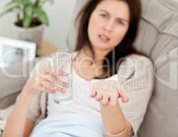 Close up of a woman taking her medicine on the sofa
