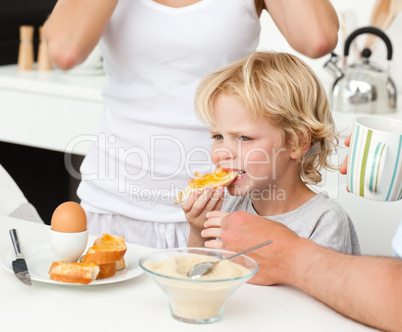 Serious boy eating a toast with marmalade during breakfast