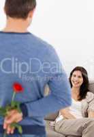 Enamored man hiding a flower behind his back for his girlfriend
