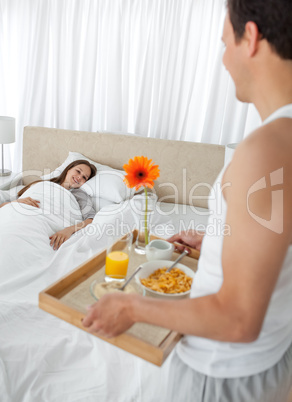 Passionate man bringing the breakfast to his girlfriend in the b