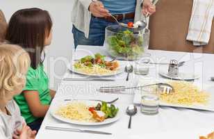 Mother serving salad to her children at lunch