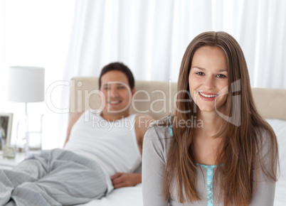 Pretty girl sitting on the edge of her bed with her boyfriend