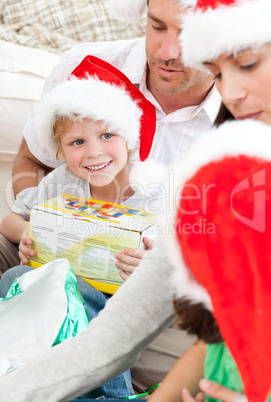 Happy boy holding a christmas gift sitting on the floor