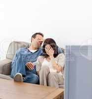 Scared couple hiding their faces while watching a horror movie