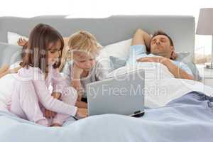 Attentive boy using a laptop with his sister while their parents