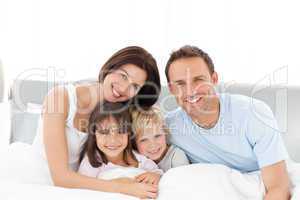 Portrait of a happy family sitting on the bed