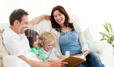 Happy parents looking at a photo album with their children