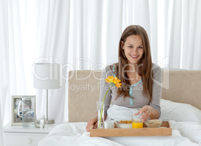 Portrait of a young woman having breakfast on the bed