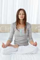 Serene woman doing yoga exercises on the bed