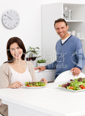 Happy couple eating a salad while drinking red wine