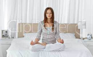 Young woman doing yoga exercises on the bed