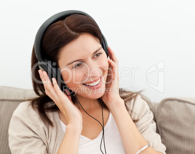Happy woman with headphones sitting on the sofa