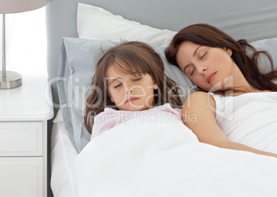 Cute little girl sleeping with her mother in the morning