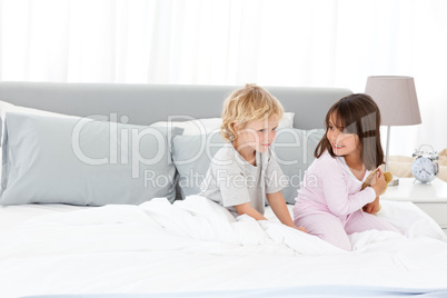 Little boy playing with his sister on their parents' bed