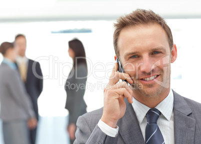 Happy businessman on the phone while his team working