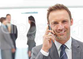 Happy businessman on the phone while his team working