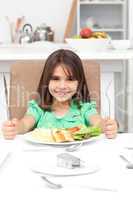 Adorable llittle girl holding forks to eat pasta and salad