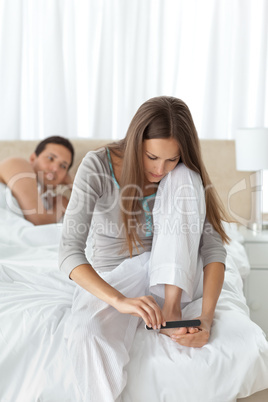 Man waiting for his girlfriend filing her toenails on the bed