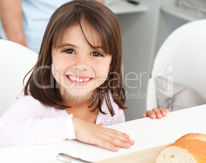 Cute little girl eating bread during breakfast